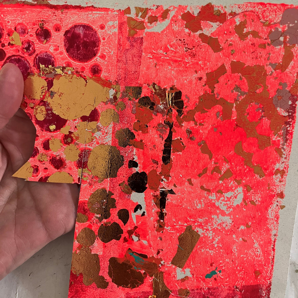 Hand holding a piece of red paper with gold and black decorative elements on a white background